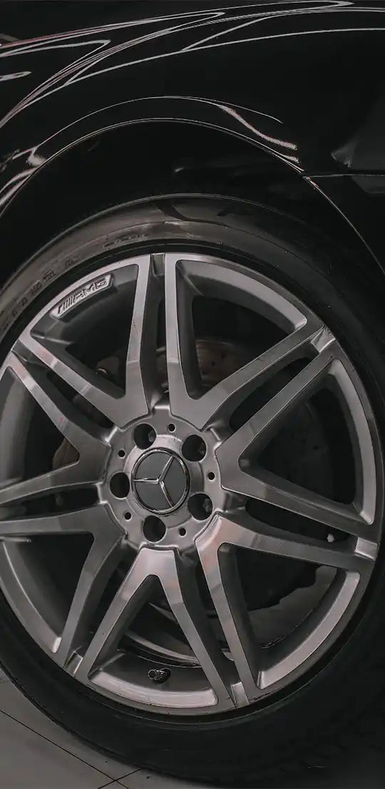 A black Mercedes-Benz car with a multi-spoke alloy wheel.
