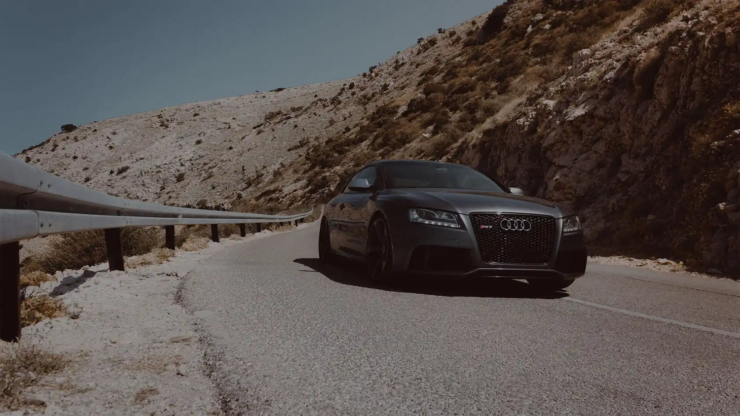Dark gray Audi sports coupe on a mountain road.
