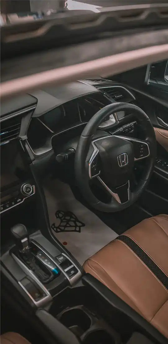 Interior view of a modern car with brown leather seats and a black steering wheel.
